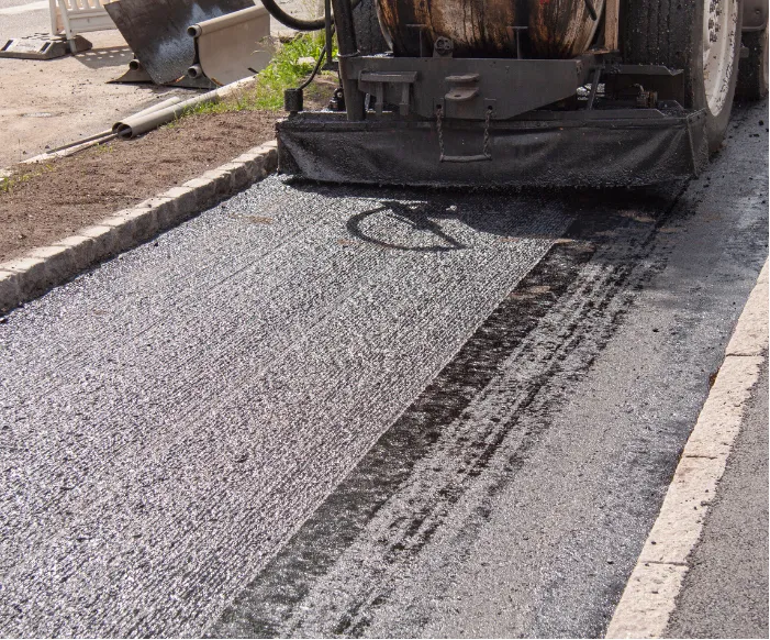 A paving machine lays fresh asphalt on a road during street construction.