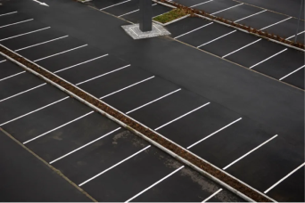 Empty parking lot with marked parking spaces and no cars, viewed from above.
